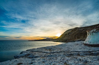 Kayalık bir kıyı şeridi olan Atlantik kıyısı. Su mavi ve gökyüzü bulutlu.