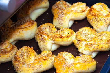 Bir tepsi susamlı hamur işi. Toplamda dokuz hamur işi var. Hepsi aynı boyut ve şekle sahip.