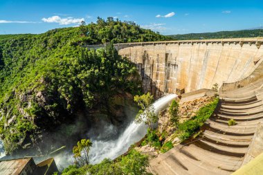 Arka planda yemyeşil bir orman olan kayalık bir uçurumdan bir şelale akıyor. Sahne sakin ve huzurlu, suyun sesiyle.