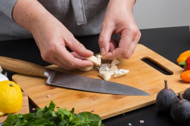 hands of the cook are peeling the garlic. close-up clipart