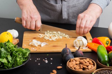 Şefin elleri kesme tahtasındaki sarımsağı kesti.