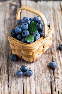 Yaban mersinleri sepetin içinde, ahşap masanın üzerinde.