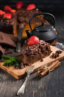 Tahta bir masada çilekli bir dilim çikolatalı pasta.