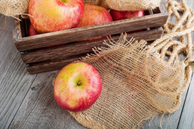Ahşap bir kutunun arka planında elmalar yakın planda.