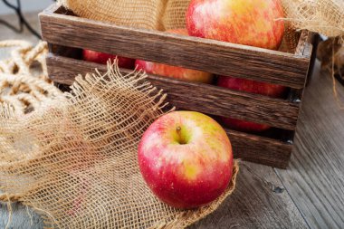 Ahşap bir kutunun arka planında elmalar yakın planda.