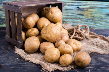 Çuvalın üstünde patates olan tahta kutu.