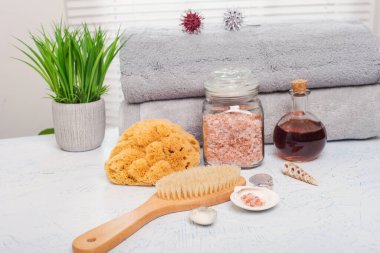 Beyaz masadaki spa aksesuarları. Yağ tuzu, bez ve fırça..
