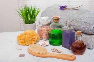 Havlular şampuanlar, yağlar ve spa aksesuarları bir kaplıca salonundaki beyaz bir masaya.