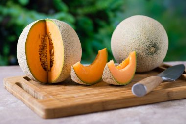 Masanın üzerinde kesilmiş bir parçayla olgun bir kavun.