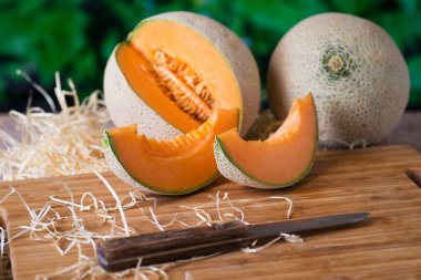 Bahçedeki ahşap masada bıçakla olgun kavun dilimleri.