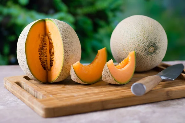 Masanın üzerinde kesilmiş bir parçayla olgun bir kavun.