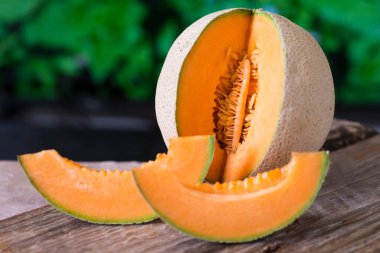 Bahçedeki ahşap bir masada olgunlaşmış sarı kavun. Yakın plan. İki dilim.