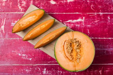 Üstünde kırmızı bir masa olan dilimlenmiş kavun. Kesme tahtasının üzerinde