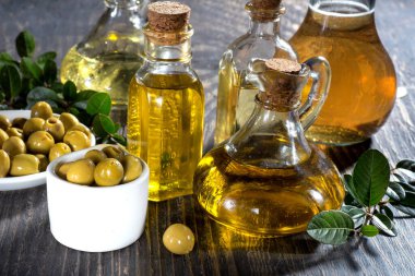 Çeşitli cam şişelerde zeytinyağı ve koyu ahşap bir masada zeytin yağı.