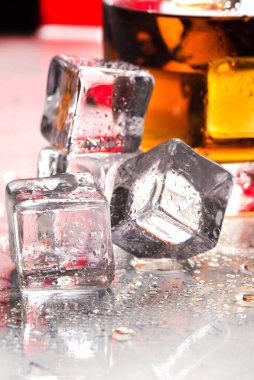 Buzların yanındaki cam masada bir bardak viski.