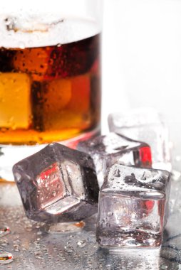 Buzların yanındaki cam masada bir bardak viski.