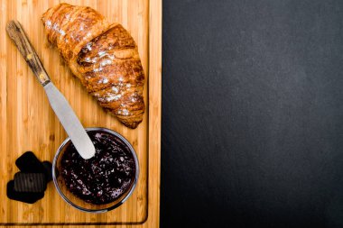 Ahududu reçelli kruvasan ve siyah arka planda çikolata. Yukarıdan görüntüle.