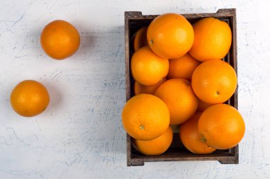 Tahta kutuda taze portakallar. Portakallar beyaz masaya. Üst görünüm portakal yığını.