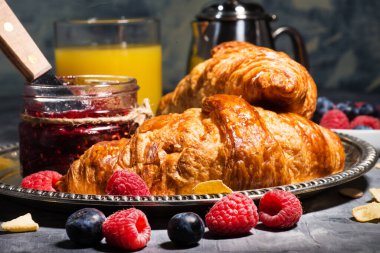 Geleneksel sağlıklı kahvaltı. Kruvasan, ahududu reçeli ve portakal suyu.