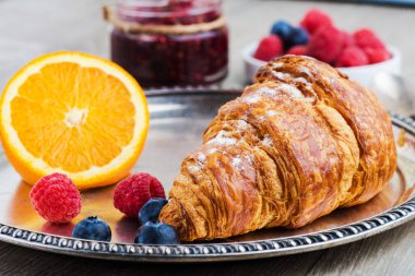 delicious breakfast with croissants, orange and raspberry jam