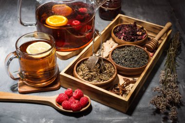 Kuru çay yaprakları, ahududular. Çaydanlıkta demlenmiş çay. gri tablo.