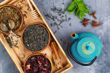 Ahşap kaselerde çeşitli bitkisel ve meyveli çaylar, gri arka plan. Yukarıdan görüntüle.