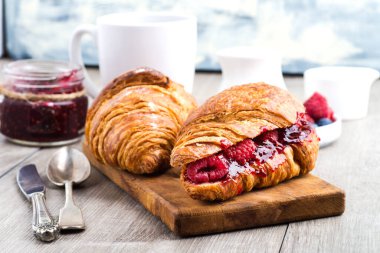 Ahududu reçelli kruvasan ve ahududu ahşap ahşap bir tahtanın üzerinde. yakın plan