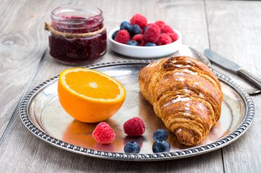 Ahududu ve ahududu reçeli ayçöreği gri bir masada gümüş bir tepside.