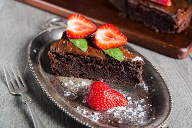 Taze çilekle süslenmiş bir dilim şekoladny pastası. Gümüş bir tabakta.