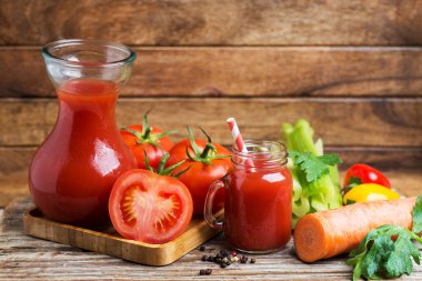 Bardakta taze domates suyu ve ahşap bir masada domatesli kokteyl pipetleri. Metin için boşluk