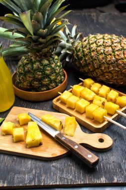 Köy ahşap bir masada olgun doğranmış ananas meyveleri. Şişede ananas suyu ve olgun ananas..