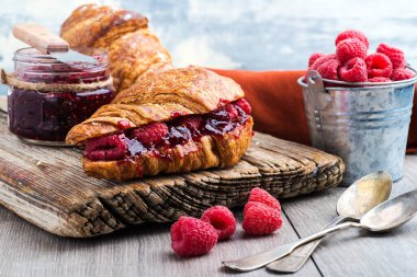 Ahududu reçelli kruvasan ve ahududu ahşap ahşap bir tahtanın üzerinde. yakın plan