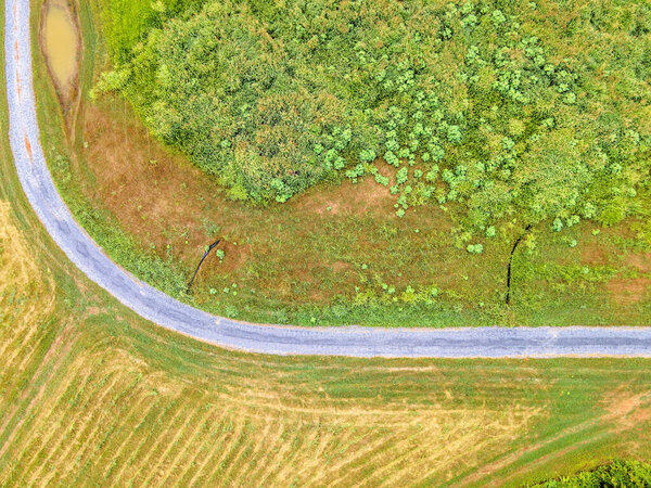Rural gravel road in summer field view from drone