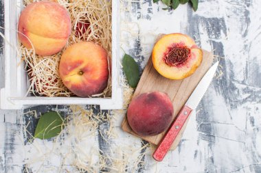 Bıçakla dilimlenmiş şeftali ve masada bir kutu şeftali. Yukarıdan görünüm