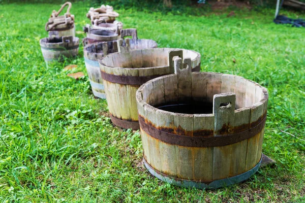 old wooden buckets of water stand on the grass. Vintage design.