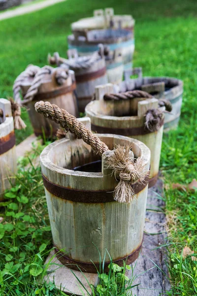 wooden buckets old and weathered with a rope handle stand on the grass close-up