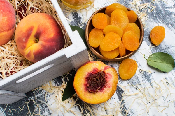 干果放在木碗里 新鲜的桃子放在灰色的桌子上 从上面看 — 图库照片
