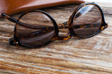 kaba ahşap arka planda modern gözlük ve deri çanta