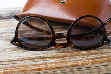 kaba ahşap arka planda modern gözlük ve deri çanta