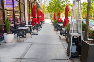 Gölgeli alandaki metal bahçe mobilyalarının üzerinde çok renkli kapalı şemsiyeler. Açık kafede huzurlu bir öğleden sonra.