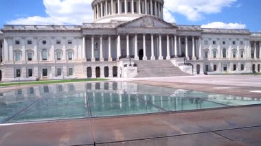  Washington, DC 'deki Amerikan Kongre Binası' nın geniş açılı manzarası, parlak bir yaz gökyüzü altında. Kamera yukarı doğru döner.