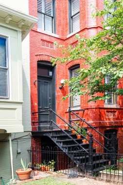 Geleneksel kırmızı tuğla dış görünüşlü, siyah demir merdivenli şehir evi.