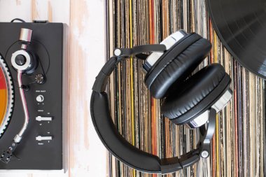 Müzik severler takımı: döner tabla, kulaklık ve renkli plak yığını.