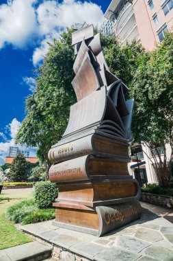 Charlotte North Carolina şehir merkezinde güneşli mavi gökyüzünün altında dramatik bronz kitap heykeli