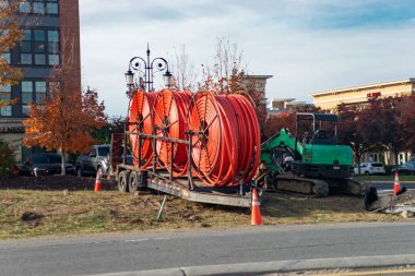 Yol kenarındaki inşaat alanındaki karavanda büyük turuncu kablo makaraları var.