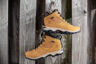 Kırsal ahşap çitlere karşı bağcıklarla asılı Timberland yürüyüş botları