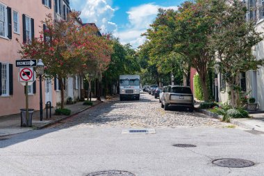 Taştan kaldırımları ve yaz yaprakları olan dar bir eski kasaba caddesinde şehir kargo aracı