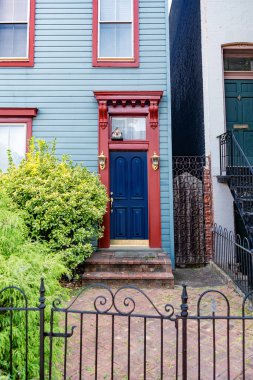 Renkli tarihi evlerin ön cephesinde parlak mavi kapının dikey fotoğrafı