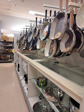 Markalı kızartma tavaları ve ev eşyaları bölümünde asılı yemek takımlarıyla dolu rafı sakla.