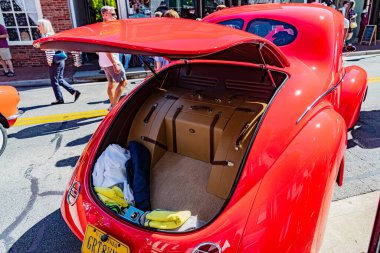 Kalabalık ve tarihi binalarla çevrili bir caddede bagajı açık 1941 yapımı bir Willys.